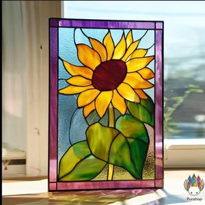 May include: Stained glass panel depicting a sunflower. The flower has yellow petals, a deep red centre, and green leaves. The panel is framed with a purple border and set against a light blue background.