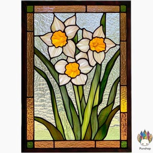 May include: A stained glass window panel featuring three white daffodils with yellow centers, surrounded by green leaves. The panel is framed in brown wood with a decorative border.