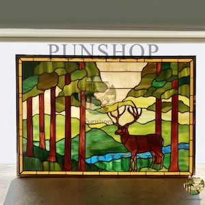 Könnte beinhalten: Buntglasfenster mit einem Hirsch in einer Waldszene. Das Kunstwerk zeigt einen braunen Hirsch mit großem Geweih, der in einem Wald mit grünen Bäumen und einem blauen Fluss steht. Das Panel ist von einem dunkelbraunen Rahmen umgeben, mit dem Text "PUNSHOP" oben.