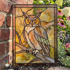 May include: A rectangular stained glass panel featuring an owl perched on a tree branch. The owl is rendered in shades of brown and cream with bright amber eyes. The background consists of swirling yellow and gold glass pieces framed in dark metal.