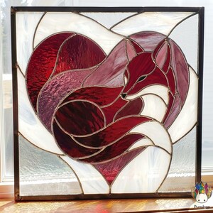 Puede incluir: Panel de vidrieras con un zorro rojo acurrucado dentro de un corazón. El zorro tiene detalles blancos y está sobre un fondo blanco y tonos de rojo. El panel está enmarcado en negro.