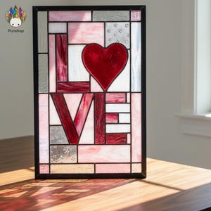 May include: Stained glass panel with the word "LOVE" and a red heart. The panel features a black frame and a mix of red, pink, white, and gray glass pieces. The design is geometric and decorative.