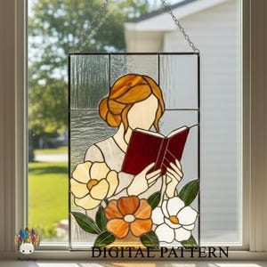 May include: Stained glass panel featuring a woman reading a book, with a floral design at the bottom. The woman has auburn hair and is wearing a light-colored top. The book is red. The panel is hanging from a chain. Text at the bottom reads "DIGITAL PATTERN".