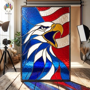 Pode incluir: Painel de vitral com uma águia careca americana e a bandeira americana. A águia é retratada com detalhes em branco, azul e amarelo, em um fundo de bandeira vermelha, branca e azul. O painel é emoldurado em metal escuro.