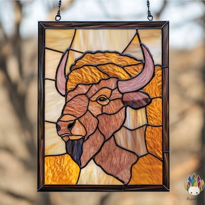 May include: A stained glass window depicting a brown and tan bison head with a detailed design. The window is framed in black metal and hangs from a chain.