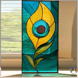 Pode incluir: Painel de vitral com um design estilizado de pena de pavão. A pena é principalmente amarela com um centro turquesa e castanho, sobre um fundo turquesa e azul. O painel é emoldurado com linhas escuras, criando uma peça de arte decorativa.