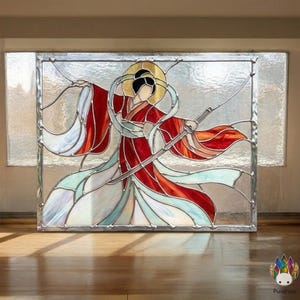 May include: Stained glass panel showing a figure in a red and white kimono holding a sword. The figure has a gold halo and is set against a background of clear and coloured glass. The artwork is framed in a silver metal.