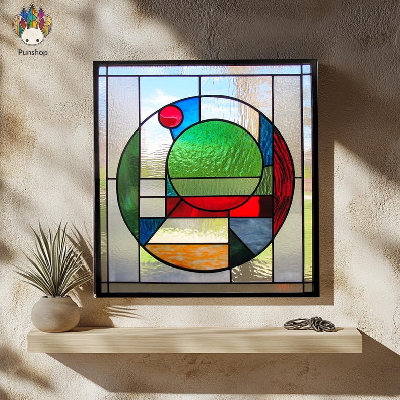 Pu&ograve; includere: Un pannello di vetro colorato con un design circolare che presenta forme geometriche in tonalit&agrave; di rosso, verde, blu e giallo. Il pannello &egrave; incorniciato in nero.