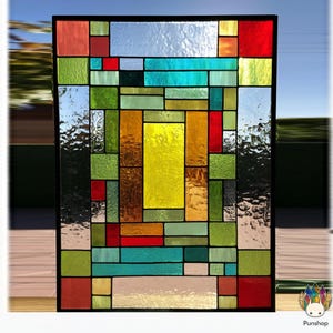 May include: A rectangular stained glass panel with a black frame. The design features an abstract arrangement of colorful glass pieces in shades of red, green, yellow, blue, and clear. The glass has varying textures and patterns.
