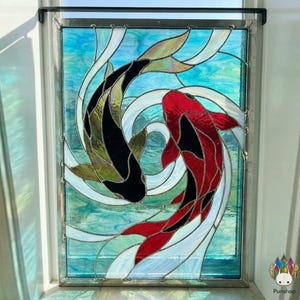 May include: Stained glass window featuring two koi fish in a yin-yang design. One fish is black with green-gold fins, the other is red with black accents. The background is a swirling blue and white pattern.