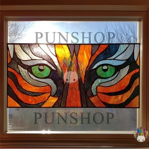 May include: Stained glass window panel depicting a tiger's face with orange, black, and white stripes. The tiger's eyes are green, and the panel has the word "PUNSHOP" at the top and bottom.