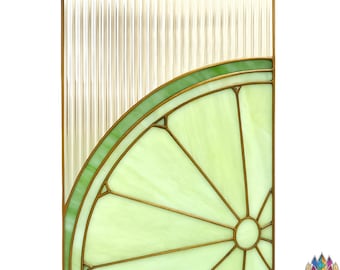 May include: A stained glass panel featuring a lime slice design. The lime slice is a light green color with a darker green outline and a gold-colored frame. The background is a textured, clear glass.