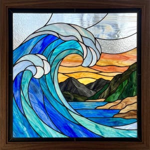 May include: A square stained glass panel in a dark wood frame depicting a large, curling ocean wave in shades of blue and white. The background features a sunset with orange and yellow hues, dark mountains, and a rocky shoreline by the water.