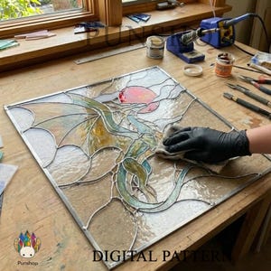 Könnte beinhalten: Ein quadratisches Buntglasfenster mit einem Drachendesign und einer rosa Sonne. Der Drache hat blaue und grüne Details. Das Panel wird mit einem Tuch gereinigt. Die Worte "DIGITAL PATTERN" stehen unten.