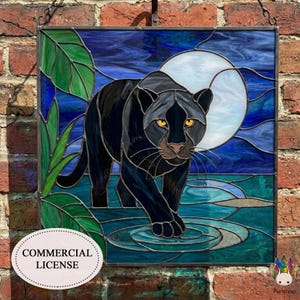 May include: Stained glass panel featuring a black panther with yellow eyes, set against a blue and white moonlit background. Green leaves and water details add to the scene. The panel is framed and hangs on a brick wall. Includes a "COMMERCIAL LICENSE" label.