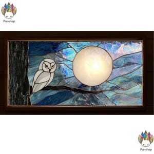 Peut inclure: Panneau en vitrail rectangulaire représentant un hibou blanc perché sur une branche, avec une pleine lune dans un ciel nocturne bleu. L'œuvre utilise des nuances de bleu, blanc et noir, encadrée de bois foncé. Design artistique et unique.