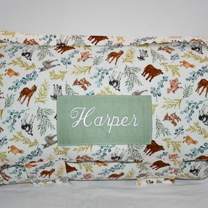 May include: A white play mat with a green personalized patch that says "Harper" and a pattern of brown and white horses, green leaves, and yellow flowers.