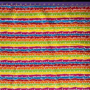 May include: Rainbow striped fabric with the words "you are loved" repeated in white on each stripe.