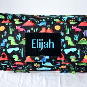 May include: A black and red dinosaur-themed play mat with a personalized name tag that reads "Elijah".