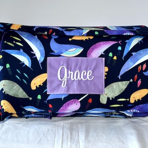 May include: A blue and purple nap mat with a sea creature design. The mat has a purple fabric name tag with the name "Grace" embroidered in white.