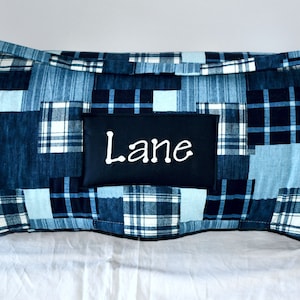 May include: Blue and white plaid fabric roll-up sleeping mat with a black fabric patch that says "Lane" in white lettering.