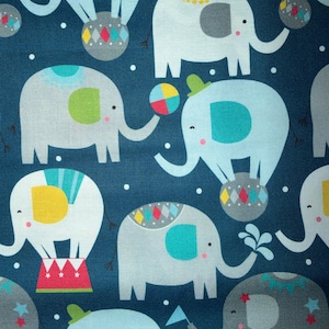 May include: A dark blue fabric featuring a repeating pattern of light blue and gray elephants. The elephants are depicted with colorful accents including yellow, teal, and red, performing circus-themed activities like balancing on balls or standing on platforms.