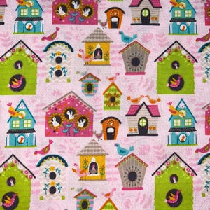 May include: A repeating pattern of colorful birdhouses and birds on a pink background. The birdhouses are various shapes and colors, including green, blue, pink, and yellow, with decorative details. Birds of different colors are perched on the birdhouses and flying around.