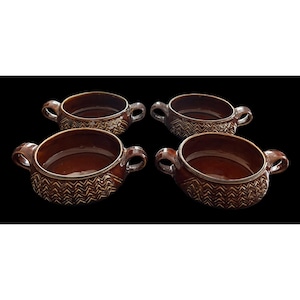 May include: Four brown ceramic soup bowls with handles. Each bowl has a decorative zig-zag pattern around the rim and on the lower exterior. The bowls are set against a black background.