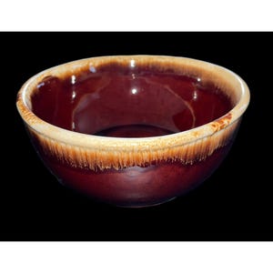 Puede incluir: Una taza de cerámica blanca con un asa negra y el texto "But First, Coffee" en un estilo manuscrito. La taza está sobre una superficie blanca. La taza mide aproximadamente 10 cm de alto.