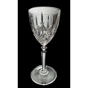 May include: A clear crystal wine glass with a starburst design on the bowl and a faceted stem. The glass has a wide base and a tall, slender stem. The glass is empty and set against a black background.