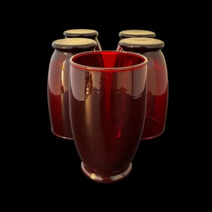 Peut inclure: Ensemble de cinq verres à boire rouge rubis. Les verres ont une forme arrondie avec un bord légèrement évasé et une base sombre. Les verres sont faits d'un matériau transparent, permettant à la lumière de passer à travers.