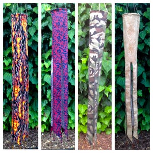 May include: Four hanging wind chimes with various designs. One features a flame pattern in red, yellow, and black. Another has a red and blue swirl pattern. The third has a camouflage pattern, and the last has a cork-like texture.