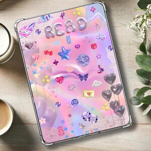 May include: A clear phone case with a pink, blue, and purple holographic background. The case is decorated with colorful stickers, including hearts, stars, balloons, and the word "READ".