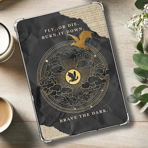 Puede incluir: Una funda para iPad negra y dorada con un diseño de dragón y el texto "Fly...or die. Burn. It. Down. Brave the dark."