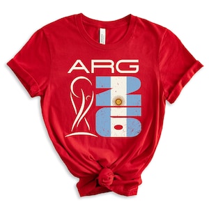 May include: A red t-shirt featuring the text "ARG" in white, with a stylized design and the number "16" in the colors of the Argentinian flag. The shirt is knotted at the bottom.