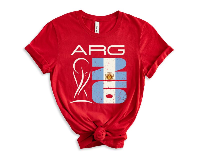 May include: A red t-shirt featuring the text "ARG" in white, with a stylized design and the number "16" in the colors of the Argentinian flag. The shirt is knotted at the bottom.