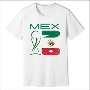 May include: White t-shirt featuring the word "MEX" in green block letters, alongside a stylized green emblem and a distressed Mexican flag design. The shirt is a classic crew neck style.