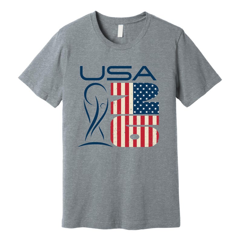 May include: A heather gray t-shirt with the word "USA" in blue, and the numbers "26" in a design resembling the American flag. A blue graphic is on the left side of the shirt.