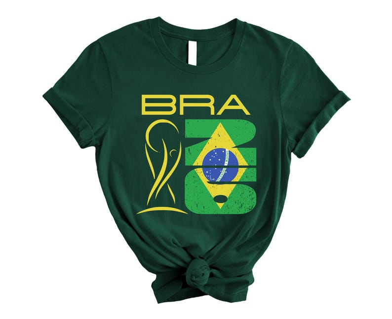 May include: Dark green t-shirt with the word "BRA" in yellow block letters above a stylized yellow figure and a green and yellow design with a blue and white circle. The shirt is knotted at the bottom.