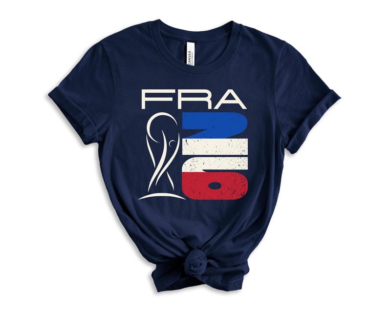 May include: Navy blue t-shirt with a graphic design. The design features the word "FRA" in white, with a stylized image and the word "NO" in the colors of the French flag: blue, white, and red. The shirt is knotted at the bottom.