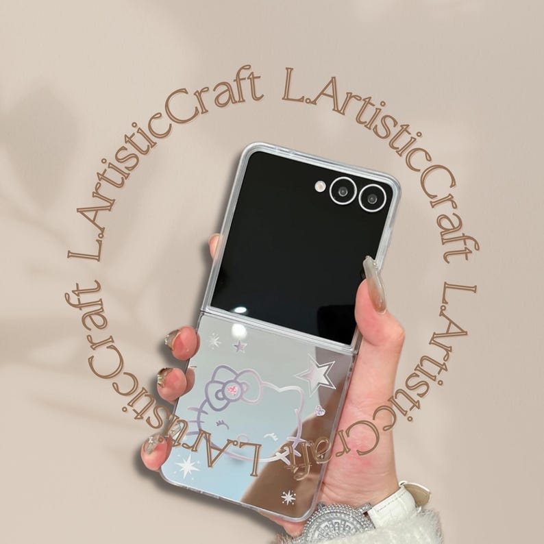 Pu&ograve; includere: Custodia per telefono trasparente con finitura a specchio, con un design di Hello Kitty e dettagli a stella. La custodia &egrave; tenuta in mano con un orologio bianco. Il testo "L.ArtisticCraft" &egrave; stampato attorno al telefono.