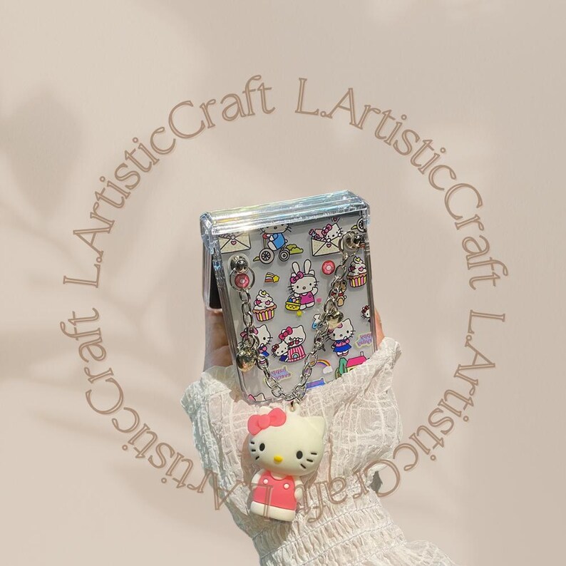 May include: A clear plastic purse with a silver chain strap and a Hello Kitty print. The purse has a Hello Kitty charm attached to the bottom.