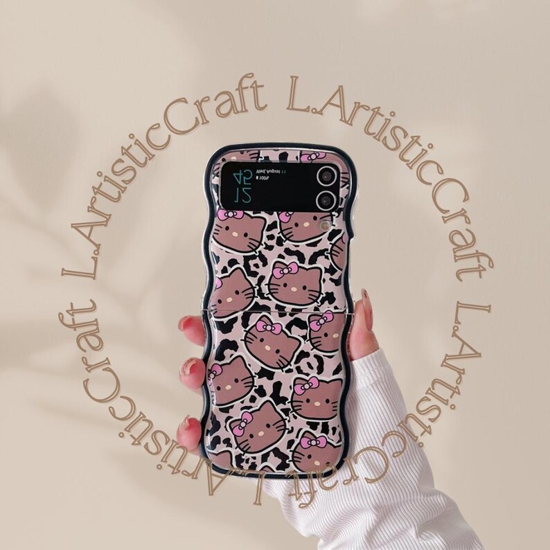 May include: A black phone case with a pink and brown leopard print and a Hello Kitty design. The case has a fold-over flap.