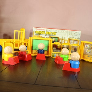 May include: A vintage yellow school bus toy set with a blue wheel, and several yellow classroom-themed accessories. The set includes figures with wooden ball heads and red, blue, and green bases. The box reads "SCHOOL BUS TOY".