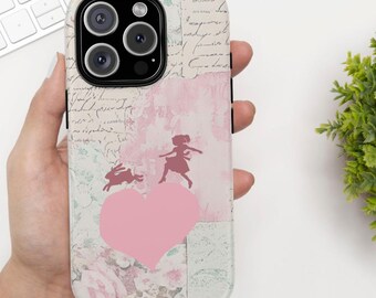May include: A pink and white phone case with a collage of vintage paper and a silhouette of a girl and a rabbit jumping over a pink heart.