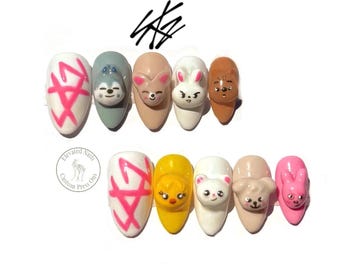 May include: A set of ten press-on nails featuring various colors and 3D character designs. Two nails display a bright pink hand-drawn logo. Other nails feature sculpted animal faces including a wolf, rabbit, bear, and chick in various shades.
