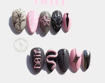 May include: A set of ten press-on nails featuring a gothic aesthetic with a color palette of black, grey, and light pink. Designs include a tree silhouette, a 3D flower, a snake, a sword, and the text "doit" in a stylized gothic font.