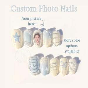 Puede incluir: Un juego de diez uñas postizas en color crema y azul claro con el texto Custom Photo Nails, Your picture here y More color options available. Los diseños incluyen una estrella, un retrato, perlas, espirales plateadas y un lazo.