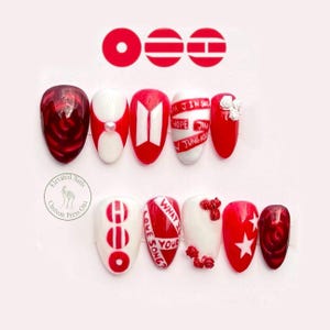 May include: A set of ten press-on nails in a red and white color palette. Designs include a deep red rose, a white nail with a pearl, the BTS logo, text reading JIN SUGA HOPE JIMIN JUNGKOOK, red roses, the text WHAT IS YOUR LOVE SONG, and stars.