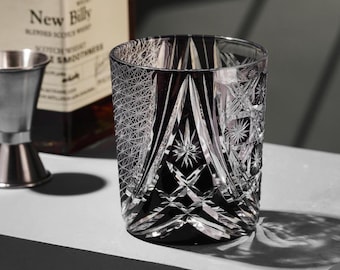 May include: A black and clear glass tumbler with a geometric pattern. The glass has a wide mouth and a thick base.